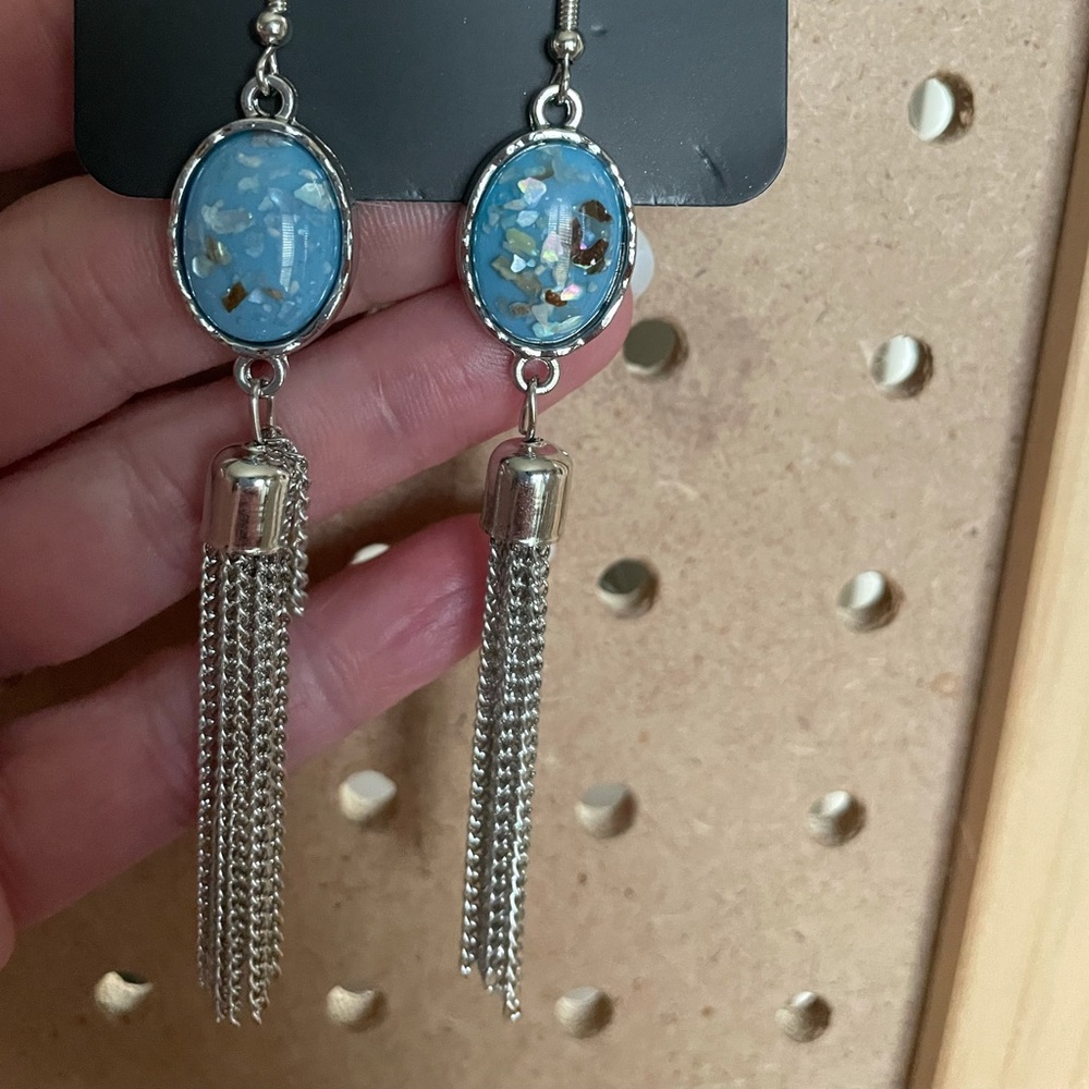 Silver earrings with blue speckled stones and silver fringe.